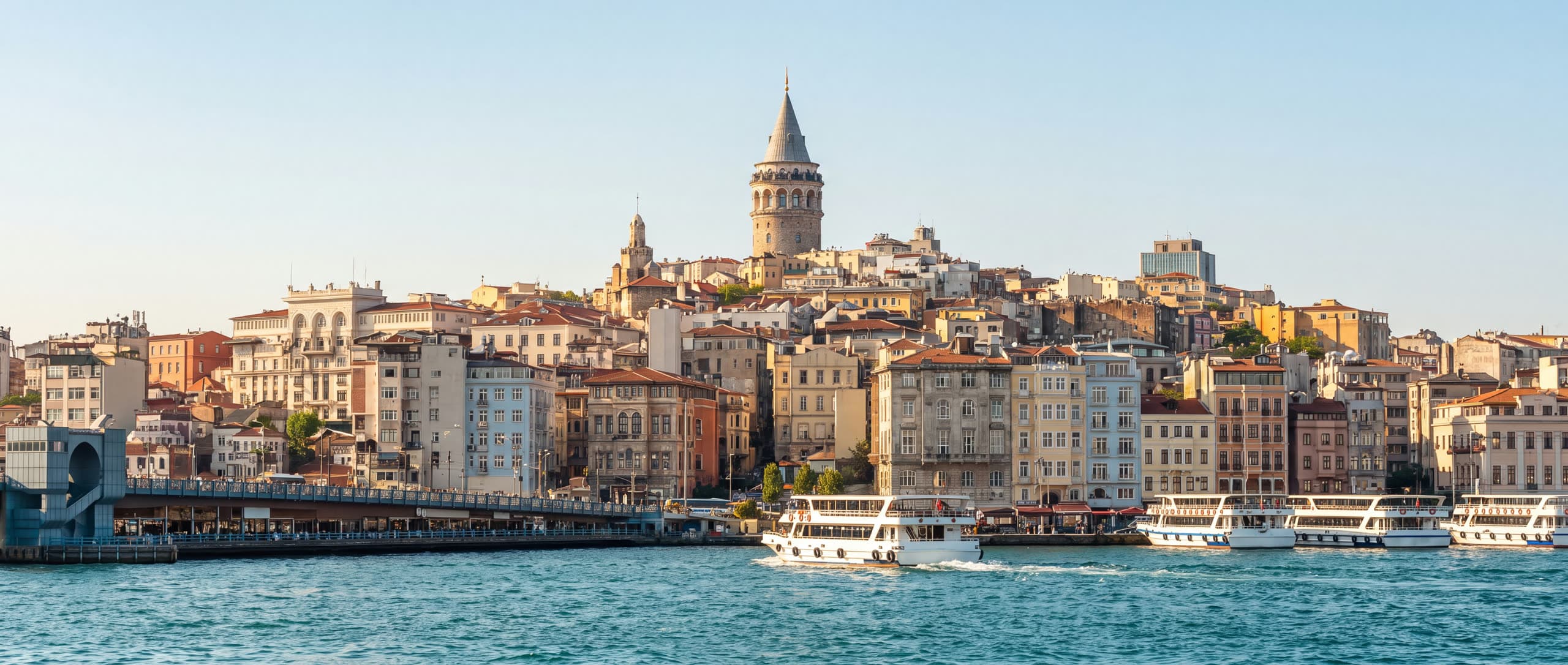 Tagespanorama des Goldenen Horns in Istanbul, mit dem über der Uferpromenade aufragenden Galata-Turm, Fähren, die die Meerenge überqueren, und der Galata-Brücke in der Ferne
